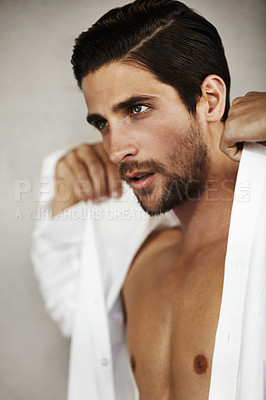 Buy stock photo Young attractive male putting on a white collared shirt