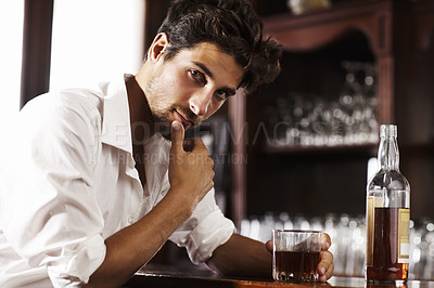 Buy stock photo Young sophisticated man drinking whiskey alone at the bar