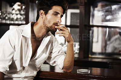 Buy stock photo Handsome man, smoking and on bar counter or cigarette burning on hand and thinking about cancer. Sexy, male person face or with ash tray or customer relaxing with nicotine and smoke idea after work