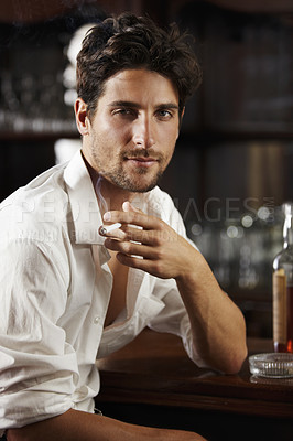 Buy stock photo Portrait, young man and smoking at a bar or cigarette at hand or handsome guy relaxing and unbuttoned shirt. Sexy, masculine and attractive model with ash tray or about to have a drink after work