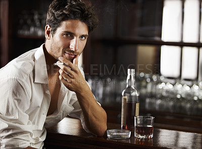 Buy stock photo Portrait, whiskey and smoking or young man or tobacco on counter and cigarette on bokeh. Sexy, masculine and male model with glass or ash tray or handsome guy relaxing with drink and smoke after work