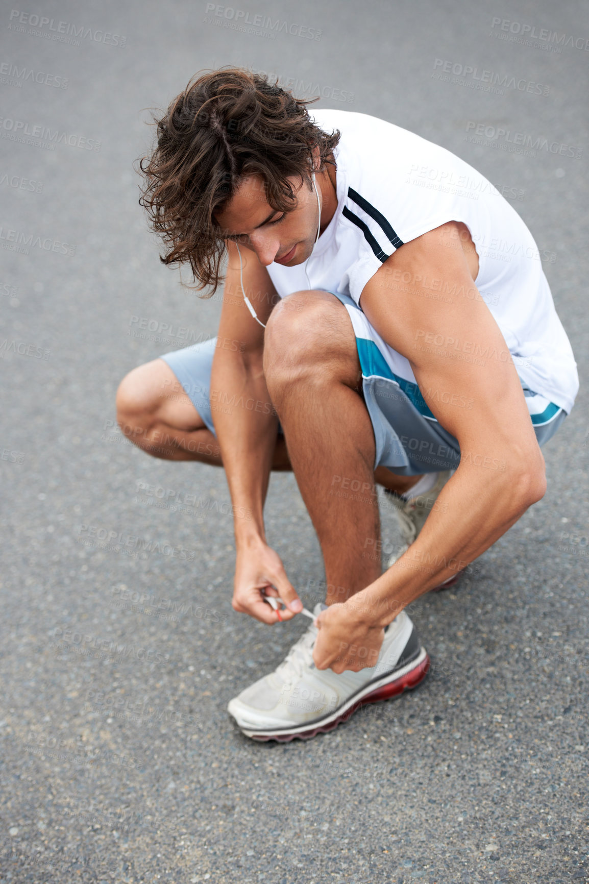 Buy stock photo Man, fitness and tie sneakers on road outdoor for running, workout and start sports performance. Runner, earphones and lace shoes on feet to prepare for exercise, cardio and marathon in city street