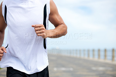 Buy stock photo A fit and athletic male running on a beach promenade outside - copyspace