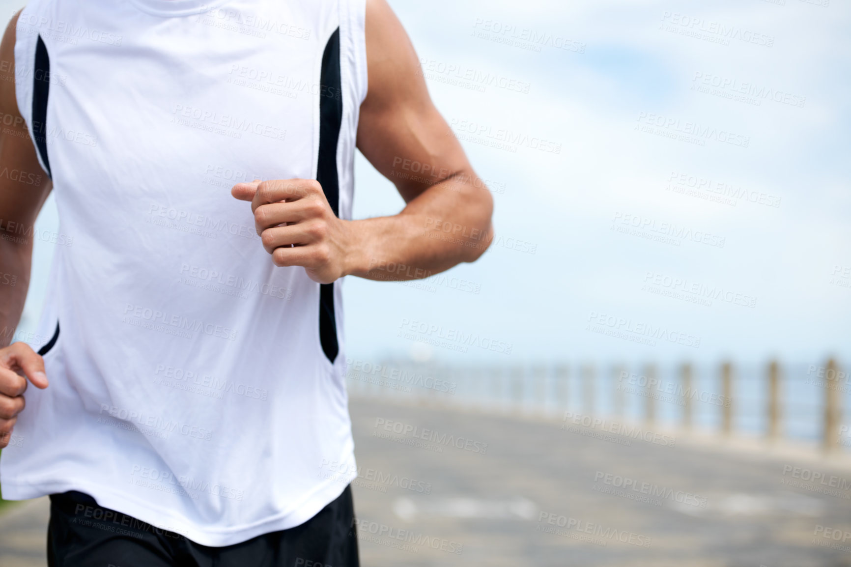 Buy stock photo A fit and athletic male running on a beach promenade outside - copyspace