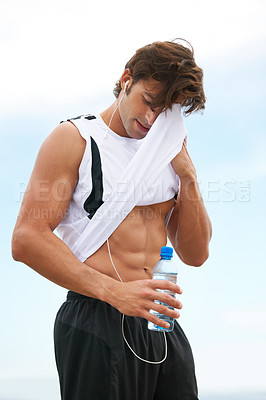 Buy stock photo Fit young man wiping his forehead with his shirt after an intense run and workout