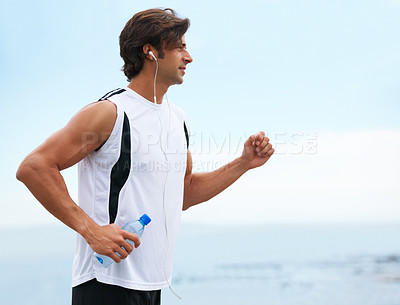 Buy stock photo Profile view of a handsome man holding a water bottle, going for a run and listening to music - copyspace