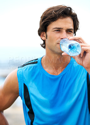 Buy stock photo A young and fit man drinking water out of a water bottle during his morning exercise routine