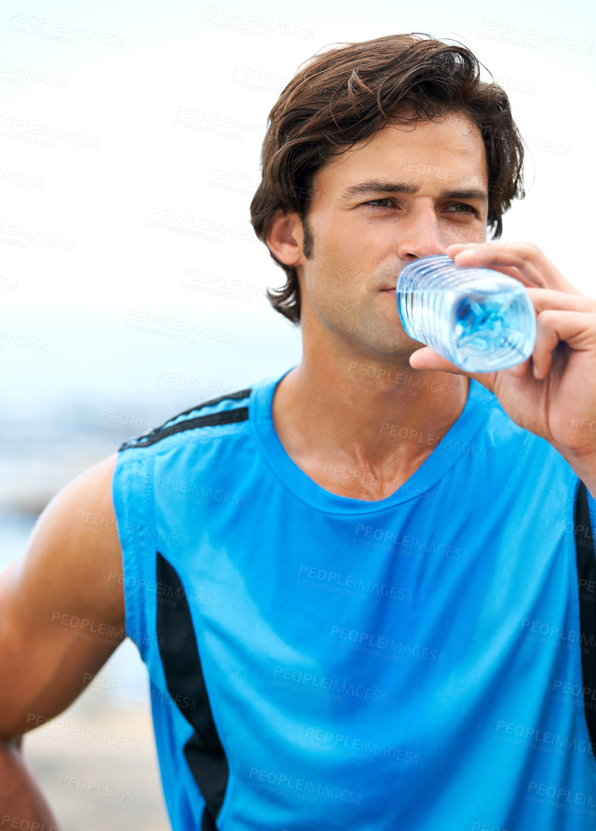 Buy stock photo A young and fit man drinking water out of a water bottle during his morning exercise routine