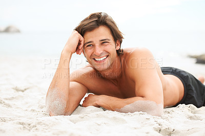 Buy stock photo Shot of a handsome young man enjoying a relaxing day at the beach