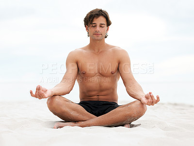 Buy stock photo Young handsome man sitting on the beach meditating