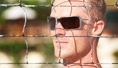 Buy stock photo Face, sunglasses and volleyball at the beach with a man by a net in summer for sports or recreation. Fitness, thinking and shades with an athlete outdoor for a game or match of competition closeup