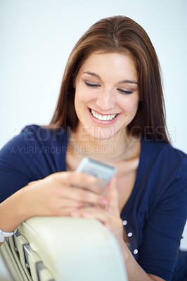 Buy stock photo A beautiful young woman sending a text message from her mobile