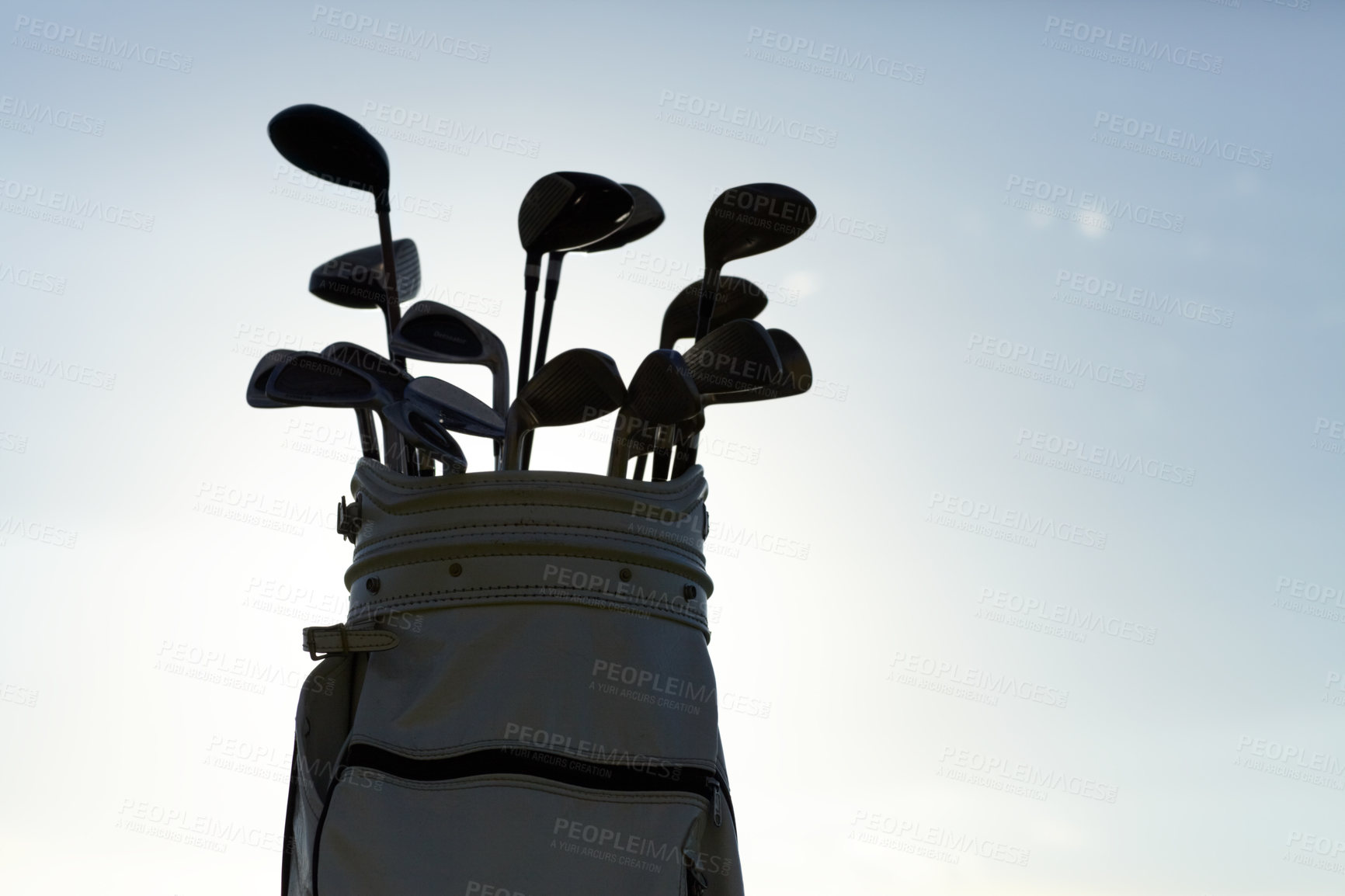 Buy stock photo Closeup of a golf bag and a variety of clubs isolated against the sky outside. Zoomed in on collection of sports equipment during the day against blue background and copyspace. Ready to practice golf