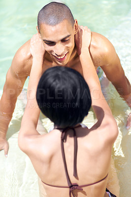 Buy stock photo An affectionate young couple in a swimming pool