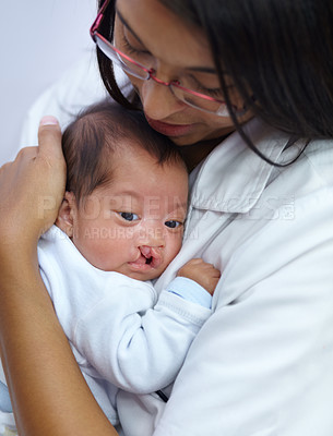 Buy stock photo Shot of a young female nurse holding a baby who has a cleft palate
