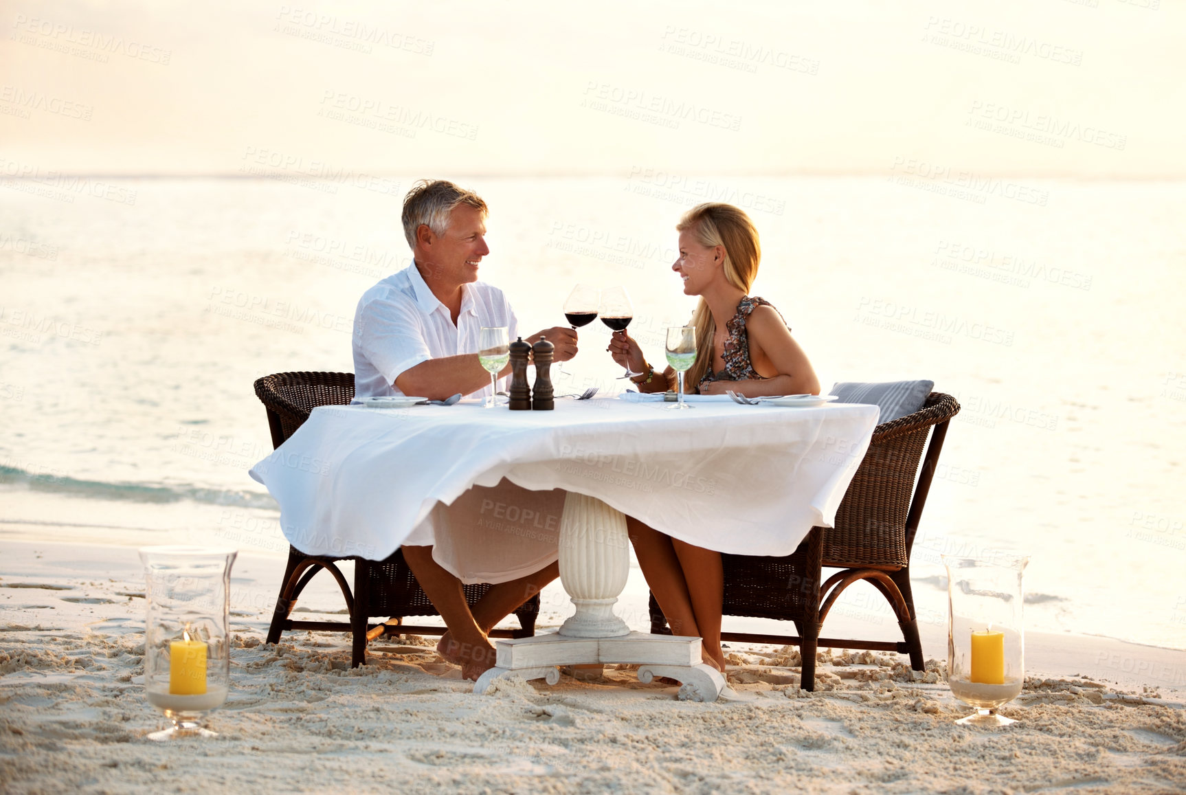 Buy stock photo Shot of a mature couple enjoying a romantic dinner on the beach