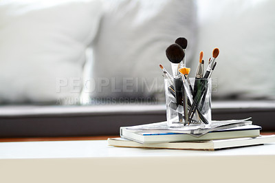 Buy stock photo A glass jar filled with make-up brushes on a pile of books