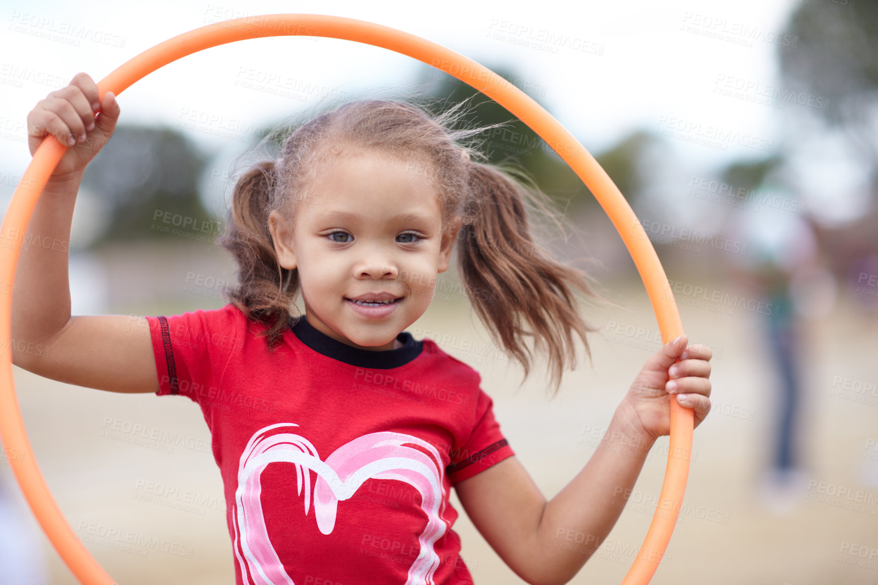 Buy stock photo Portrait of girl holding a hoola hoop outside in a playground. Cute smiling preschooler playing on a summer day during school vacation. Active african child having fun against a blurred background