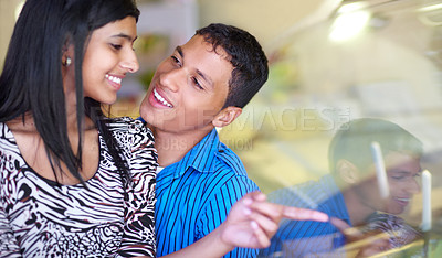 Buy stock photo Shot of an affectionate young couple looking at ice cream through the window of a shop
