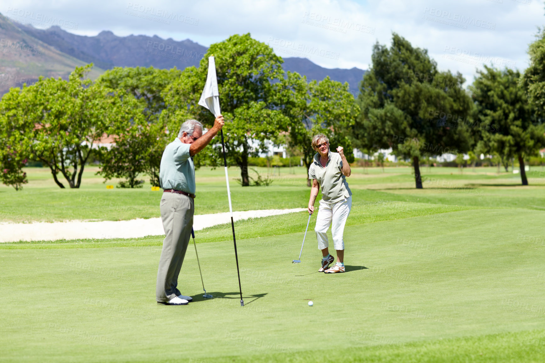 Buy stock photo A senior lady holding up her fist in disappointment as she just misses the hole during a game of golf