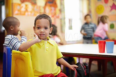 Buy stock photo Portrait of a cute ethnic boy posing for his picture at the table of a pre-school classroom
