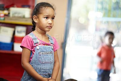 Buy stock photo A small cute pre-school girl looking at something off camera and seems to be lost in thought in her pre-school classroom