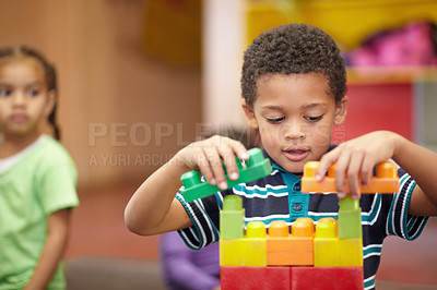 Buy stock photo An interested pre-school child building something with plastic blocks