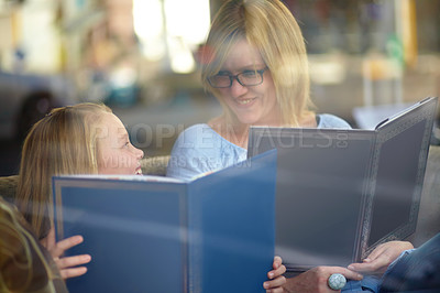 Buy stock photo Reading, books and mother with child in library with smile, learning and relax with study knowledge. Storytelling, happy mom and girl in bookstore together with story, fantasy and education in window