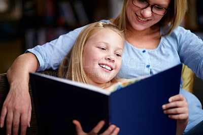 Buy stock photo A cute young girl sitting next to her mother while they read a book