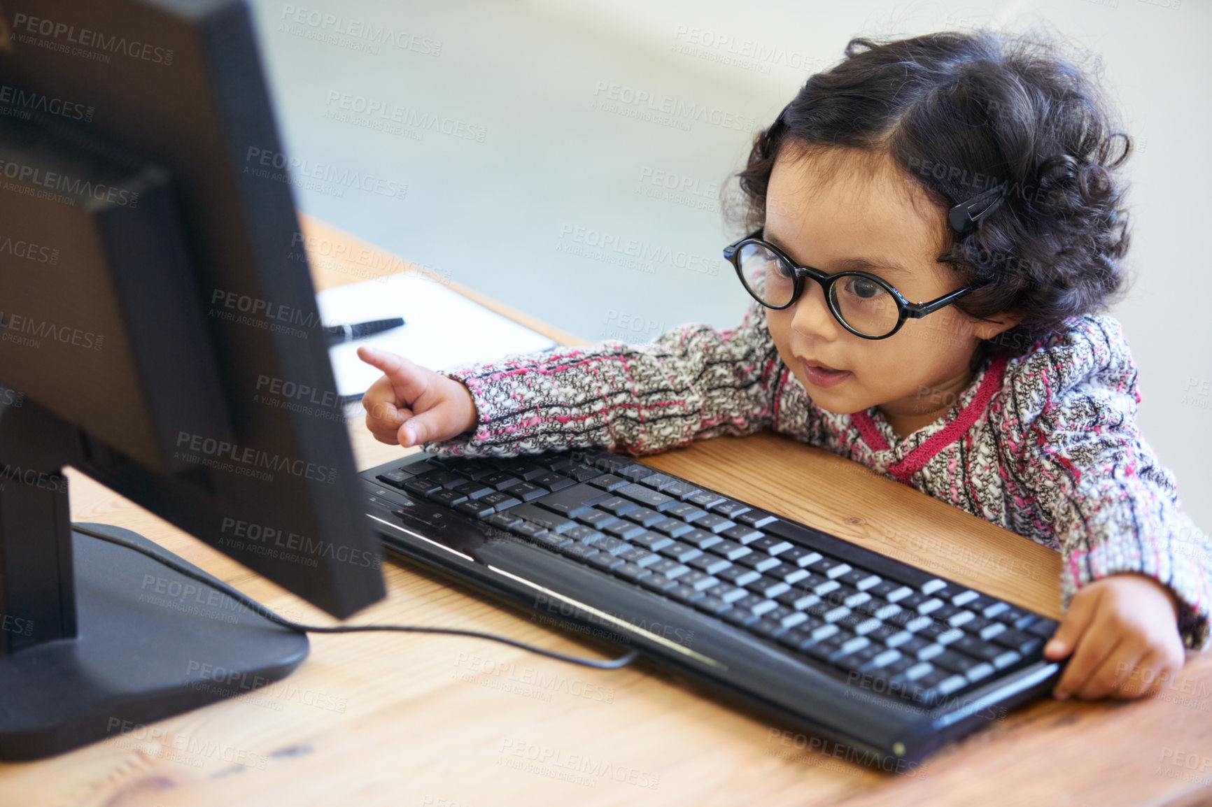 Buy stock photo Playing, learning and a child reading from a computer for communication, education or the web. House, pretend work and a girl, kid or baby with a pc at a home table for play, smile and the internet