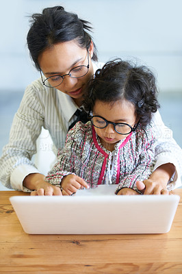 Buy stock photo A cute little girl sitting on her mother&amp;#039;s lap while working on the computer