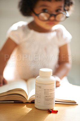 Buy stock photo Girl, child and reading or book pill bottle or adhd diagnosis, learning or development. Kid, glasses and childhood discipline story knowledge concentration, medical capsules or thinking at school