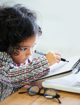 Buy stock photo Drawing, art and a child with a book for notes, creativity and learning at a table. House, study and a girl, kid or baby writing in a notebook for education, inspiration or a picture on paper at home