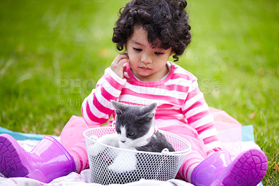 Buy stock photo Thinking, picnic and a girl in the park with her kitten together for love, care or bonding during summer. Basket, cat or kids and a curious young child in the garden having fun with her pet animal