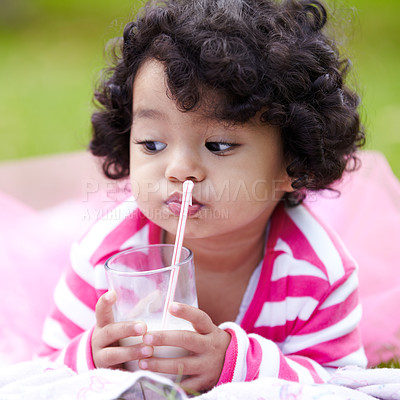 Buy stock photo Child, milk and glass with straw on grass for drink of dairy while lying for picnic in park. Girl, pink tutu and thinking of delicious beverage for growth, development and nutrition high in calcium