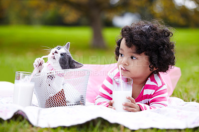 Buy stock photo Milk, picnic and a girl in the park with her kitten together for love, care or bonding during summer. Summer, straw or kids and happy young child in the garden drinking from a glass with her pet cat