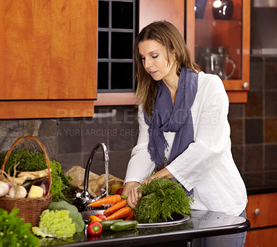 Buy stock photo Attractive woman washing fresh vegetables in her kitchen sink