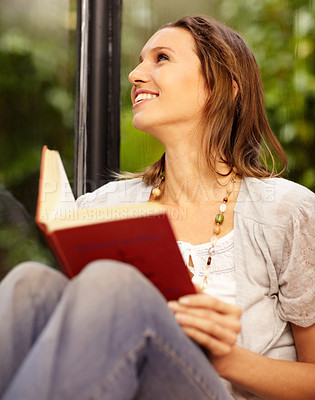 Buy stock photo A beautiful woman reading while sitting next to a window