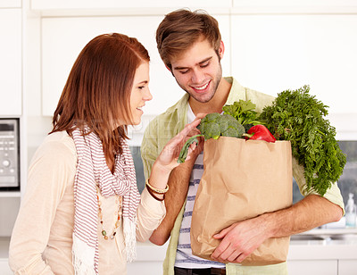 Buy stock photo A young couple holding fresh groceries in the kitchen