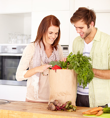 Buy stock photo A happy couple in the kitchen with their newly-bought groceries