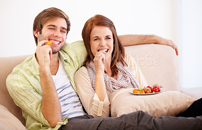 Buy stock photo A young couple relaxing on the sofa with a healthy snack