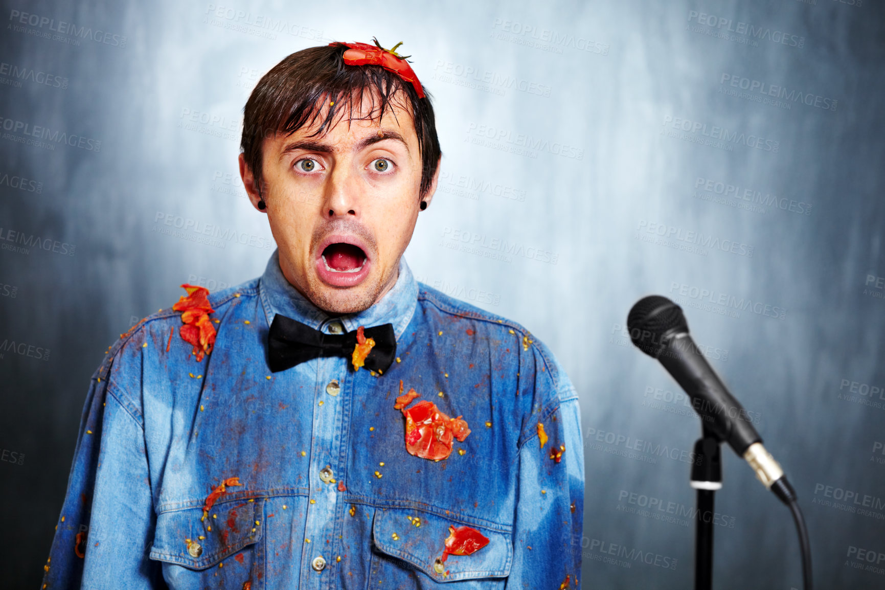 Buy stock photo Portrait of a bad standup comedian covered in rotten tomatoes