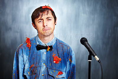 Buy stock photo Portrait, sad and a man comic in tomato with a microphone after a bad performance at a comedy club. Depression, fail or boo with an unhappy young comedian in studio on a gray background for a show