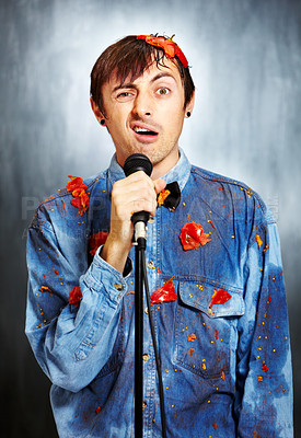 Buy stock photo Portrait of an unsuccessful standup comedian covered in rotten tomatoes