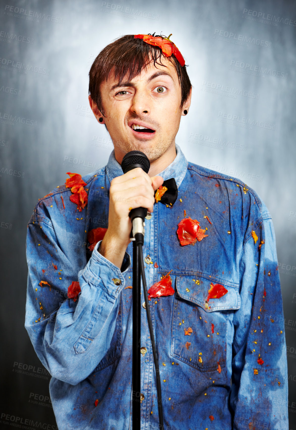 Buy stock photo Portrait of an unsuccessful standup comedian covered in rotten tomatoes