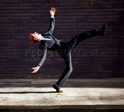 Buy stock photo A young businessman tripping on a banana peel