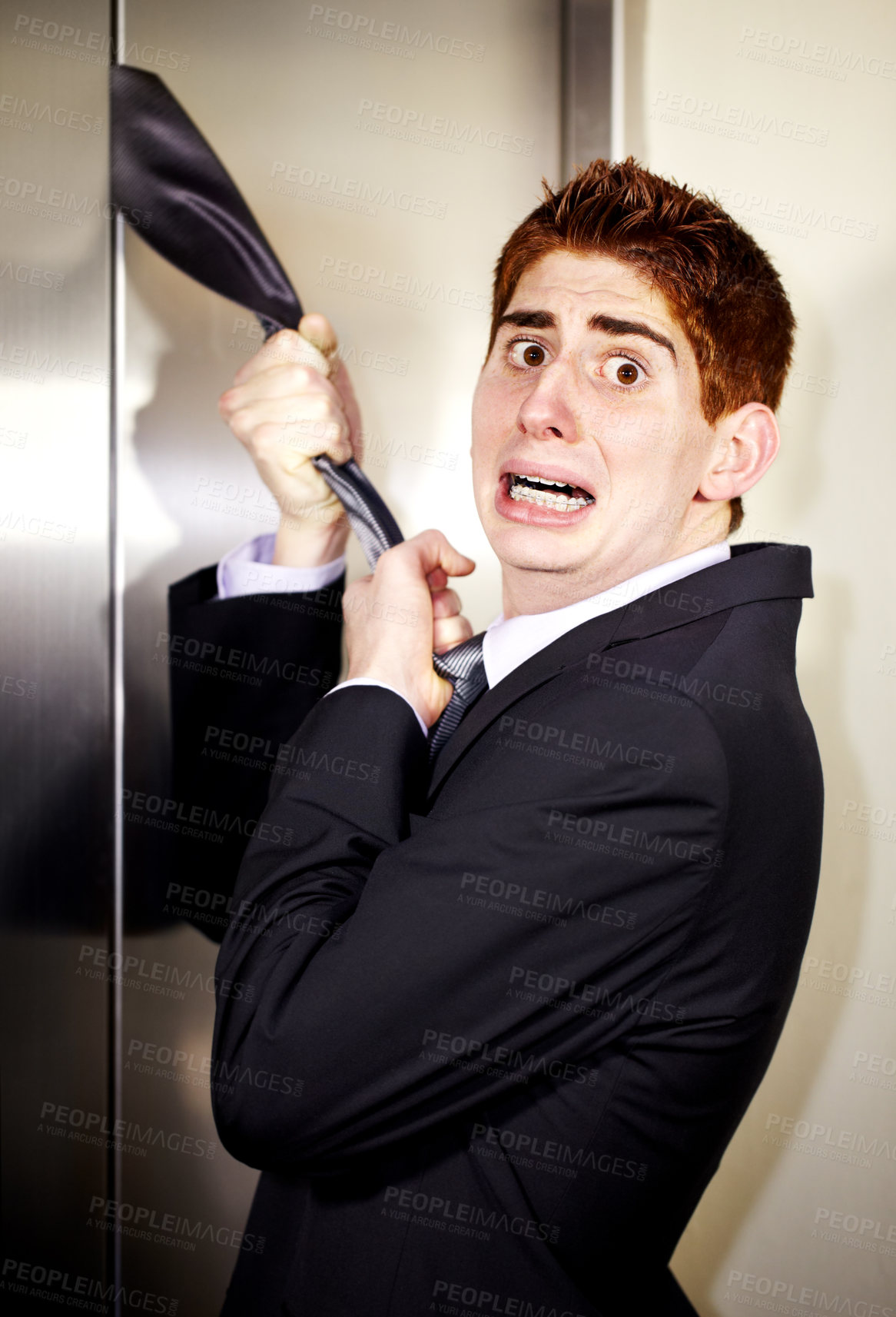 Buy stock photo A young businessman with his tie stuck in the elevator