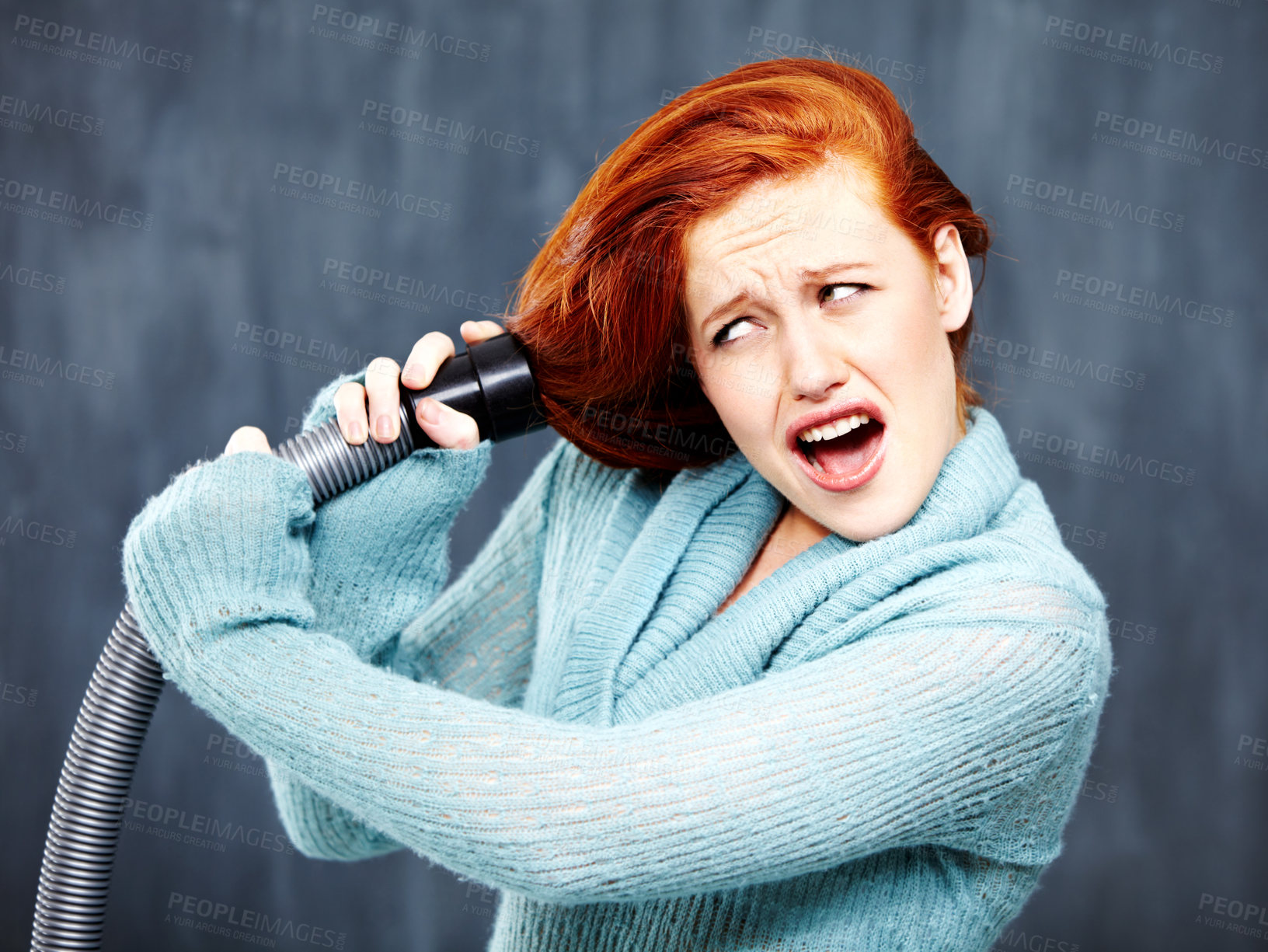 Buy stock photo A young redhead with her hair caught in the vacuum cleaner