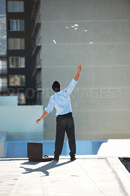 Buy stock photo Back, financial freedom and money rain with a businessman in the city, throwing cash during a summer day. Finance, success or raining dollars with a person on the roof of a building in an urban town