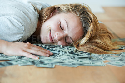 Buy stock photo A smiling girl with her eyes closed lying down on the floor with her head in a pile of money